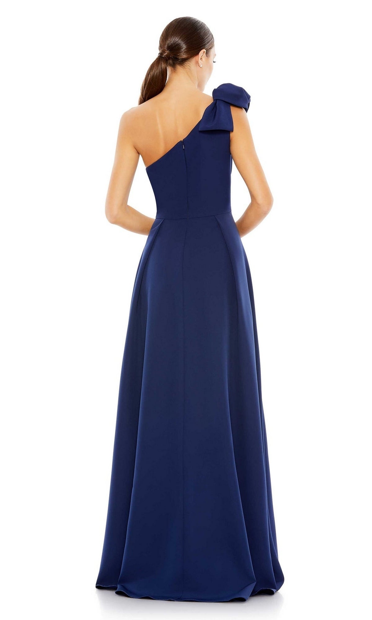 A woman is seen from the back against a white background, wearing the Mac Duggal 26989 Long Formal Dress—a floor-length, one-shoulder navy blue gown with a bow detail and an elegant A-line silhouette.